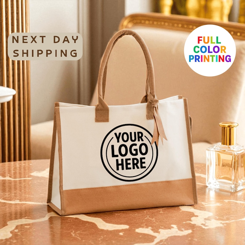 A white tote bag with a black logo printed on it, placed on a marble surface.