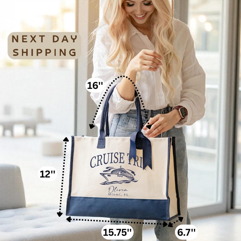 A smiling woman holding a large tote bag with a cruise ship design, standing in front of a window.