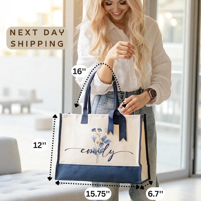 A smiling woman holding a large tote bag with a floral design, standing in front of a window.