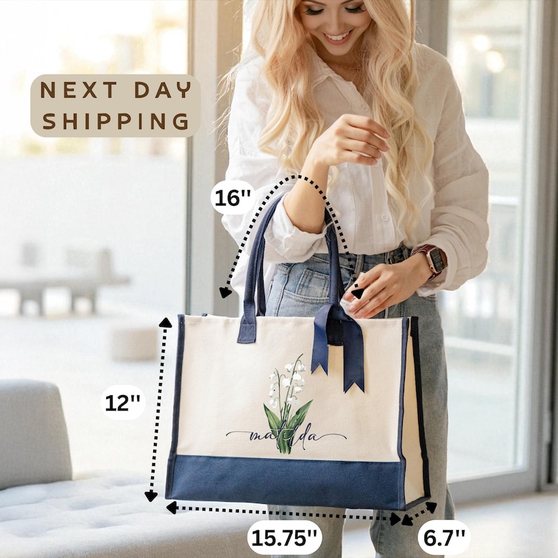 A smiling woman holding a large tote bag with a floral design, standing in a room with a window.