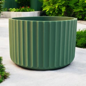 May include: A green, cylindrical planter with vertical ribbed detailing. The outdoor container is made of a solid material and has a rounded base. The planter is suitable for various plants and adds a touch of modern design to any garden or patio.