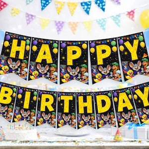 May include: A festive birthday party scene with a "HAPPY BIRTHDAY" banner in yellow letters against a black background. The banner features cartoon characters. Balloons and colorful decorations complete the celebratory atmosphere.