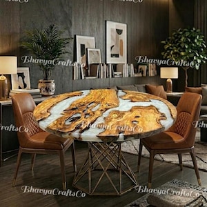 May include: A circular dining table with a distinctive wood and resin design. The tabletop showcases a natural wood grain pattern with white resin highlights. The table is supported by a gold-coloured, geometric metal base. Two brown leather chairs are placed around the table.