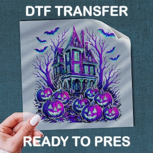 May include: A DTF transfer sheet featuring a haunted house illustration with purple and blue tones, surrounded by bare trees, flying bats, and several glowing jack-o'-lanterns. The text DTF TRANSFER READY TO PRESS is printed on the sheet.