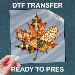 May include: A DTF transfer sheet featuring a central maple leaf graphic composed of various patchwork patterns in shades of orange, brown, green, and cream. The text DTF TRANSFER and READY TO PRES is printed in white capital letters above and below the leaf.