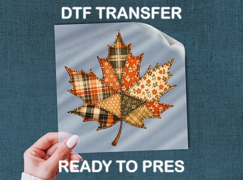A hand holding a piece of paper with a colorful autumn leaf design on it, with the text "DTF TRANSFER READY TO PRES" above the leaf.