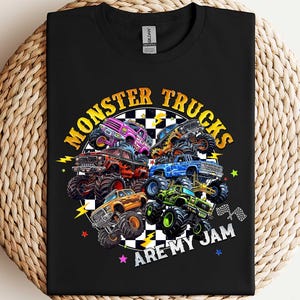 A black t-shirt with a graphic design featuring various monster trucks and the text "MONSTER TRUCKS ARE MY JAM" printed on it.