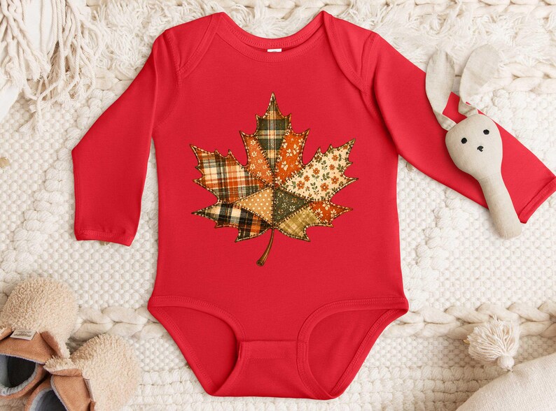 A red onesie with a leaf design, a stuffed rabbit, and a pair of beige slippers are arranged on a white surface.