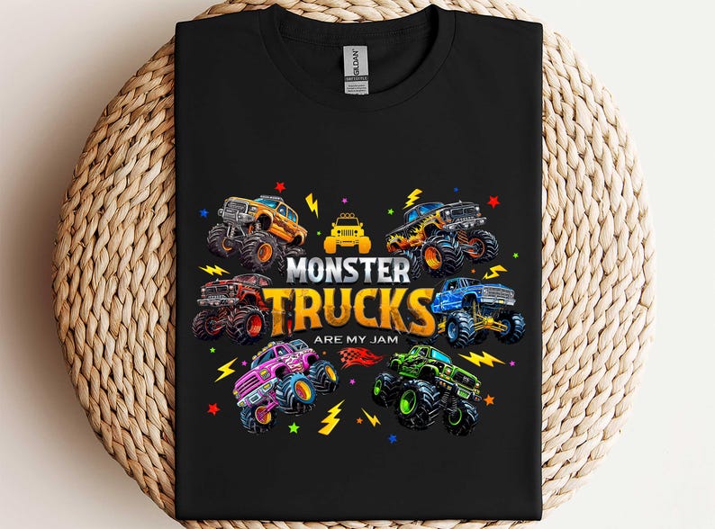 A black t-shirt with a colorful graphic design featuring various monster trucks and the text "MONSTER TRUCKS ARE MY JAM" printed on it.