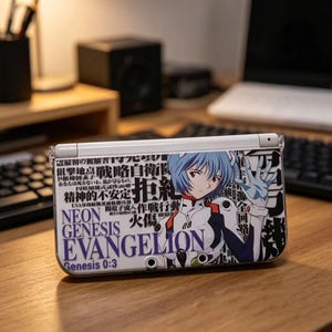 Puede incluir: Una consola de juegos portátil blanca con una carcasa personalizada. La carcasa presenta un personaje de anime con cabello azul y el texto "NEON GENESIS EVANGELION". El diseño incluye texto japonés y una paleta de colores blanco, azul y rojo.