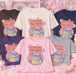 May include: A collection of t-shirts in various colors, including brown, cream, navy, purple, pink, and gray. Each shirt features a cartoon turtle wearing sunglasses and holding bubble tea, with the text "Bubble Tea Time".