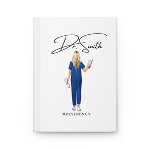 May include: White journal with a graphic of a blonde person in blue scrubs holding a tablet and stethoscope. The journal cover has the text "Dr. Smith" in cursive and the hashtag "#RESIDENCY".