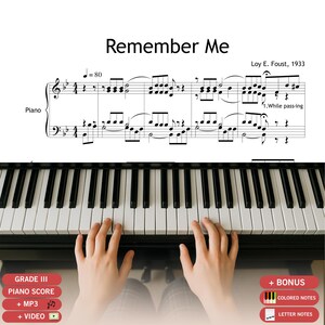 May include: A piano score titled "Remember Me" with musical notes and the text "Loy E. Foust, 1933." The image shows a piano keyboard with hands playing the keys. Additional text includes "GRADE III PIANO SCORE" and "+ MP3 + VIDEO."