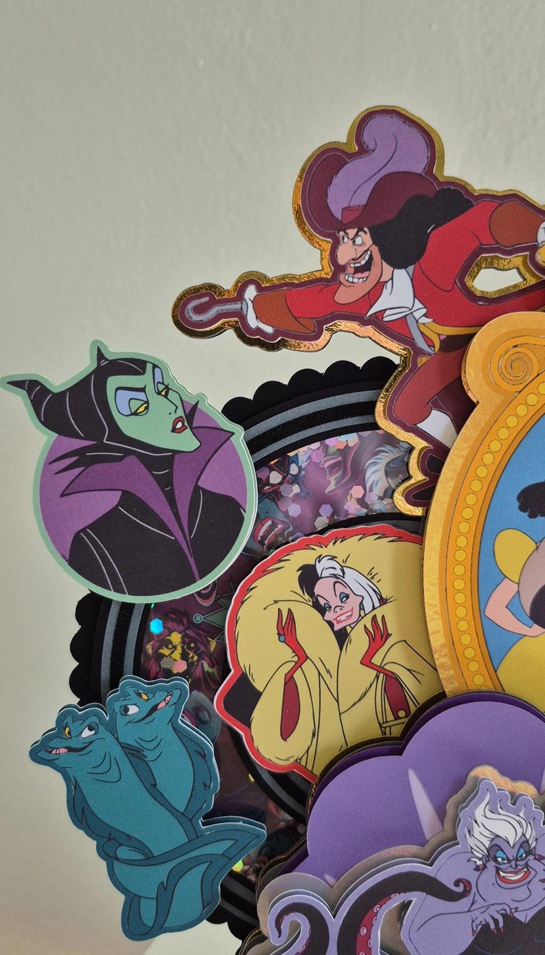 May include: A collection of colorful, die-cut character images, including Captain Hook, Maleficent, Cruella de Vil, and Ursula. The images are layered and feature gold foil accents, with a variety of shapes and sizes. The overall theme is Disney villains.