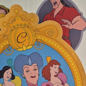 May include: Colorful die-cut character cutouts from the animated film Cinderella. Includes images of Cinderella, the stepmother, and Gaston. The characters are set against a light background.