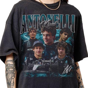 May include: Dark grey t-shirt with a collage of images of a young man, with the name "ANTONELLI" in teal above the images. The design includes a Formula 1 race car and a signature.