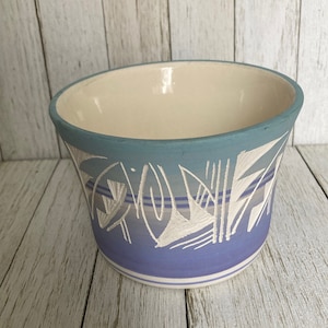 May include: A blue and white ceramic planter with a geometric design. The planter is glazed and has a white interior.
