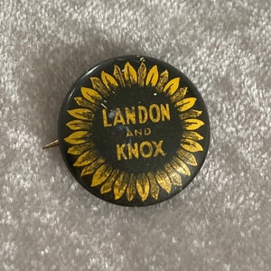 May include: A black and gold political campaign button with a sunflower design. The text on the button reads "Landon and Knox".
