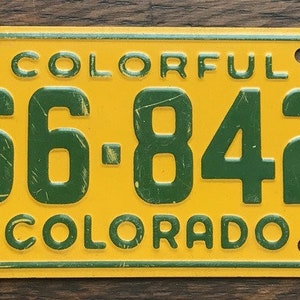 May include: A yellow and green Colorado license plate with the number 66-842 and the year 1953. The plate has the word "COLORFUL" at the top and "COLORADO" at the bottom.