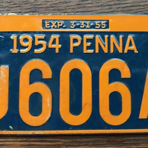 May include: A blue and orange Pennsylvania license plate from 1954 with the number J606A and the expiration date 3-31-55.