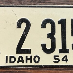 May include: A vintage Idaho license plate with black lettering on a white background. The plate number is 1A 2315 and the year is 54.