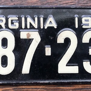 May include: Black and white Virginia license plate with the year 1954 and the number 987-232.