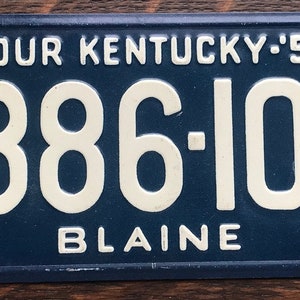 May include: Blue and white Kentucky license plate with the number 886-101 and the text "TOUR KENTUCKY: '53" and "BLAINE".