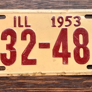 May include: A vintage Illinois license plate from 1953. The plate is cream colored with red lettering. The plate number is B32-486.