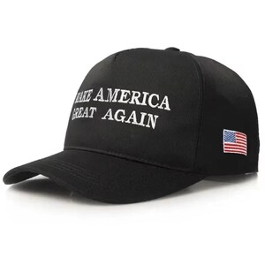 Puede incluir: Gorra de b&eacute;isbol negra con el texto blanco "MAKE AMERICA GREAT AGAIN". La gorra tiene una visera curva y un peque&ntilde;o parche de la bandera estadounidense en el lateral.