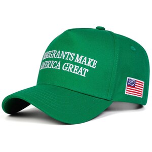 Puede incluir: Gorra de b&eacute;isbol verde con la frase bordada en blanco "IMMIGRANTS MAKE AMERICA GREAT". La gorra presenta un peque&ntilde;o parche de la bandera estadounidense en el lateral.