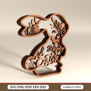 Könnte beinhalten: Ein mehrschichtiger Osterhasen-Ausschnitt aus Holz mit den Worten "Frohe Ostern" und floralen Akzenten. Der Hase ist hellbraun mit einer dunkleren braunen Umrandung. Das Design beinhaltet ein Osterei und Blätter.