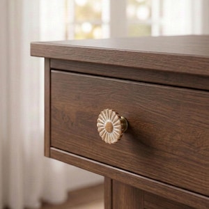 May include: A dark brown wooden nightstand featuring a single drawer with a circular, flower-shaped knob. The knob has a distressed white and gold finish with a textured, petal-like design centered on the front of the drawer panel.