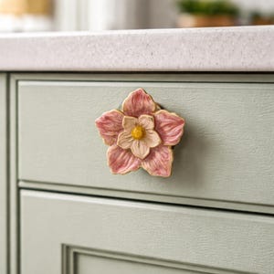 May include: A set of three ceramic mugs with a speckled, matte finish. The mugs are in shades of cream, light gray, and dark gray. Each mug has a simple, modern design and a rounded handle. The mugs are likely for coffee or tea.