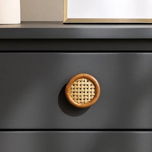 May include: A close-up of a dark gray drawer with a round wooden knob. The knob features a woven rattan center surrounded by a wooden frame. The knob is centered on the drawer, casting a shadow.