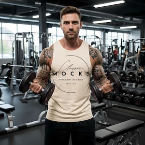 May include: A cream-coloured vest top with the text "Classic Mocks Mockup Studio Estd 2022" in a gym setting. The person is holding two black dumbbells. The background includes gym equipment.
