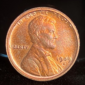 Puede incluir: Una moneda de cobre de 1905 de Lincoln. El anverso presenta un perfil de Abraham Lincoln, con las palabras "LIBERTY" y "IN GOD WE TRUST". También se muestra el año "1905".