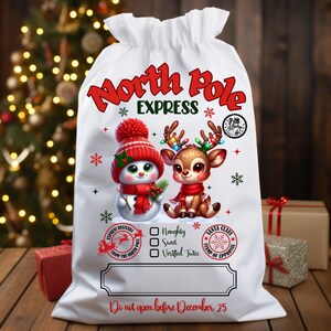 May include: White Christmas gift bag with a drawstring closure. The bag features a snowman and reindeer graphic, the words "North Pole Express", and the text "Do not open before December 25". The bag is decorated with snowflakes and Christmas-themed stamps.