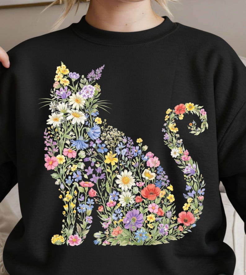 May include: Black sweatshirt featuring a floral cat design. The cat silhouette is filled with colorful flowers, including daisies, poppies, and lavender. The flowers are in shades of pink, yellow, blue, and purple.