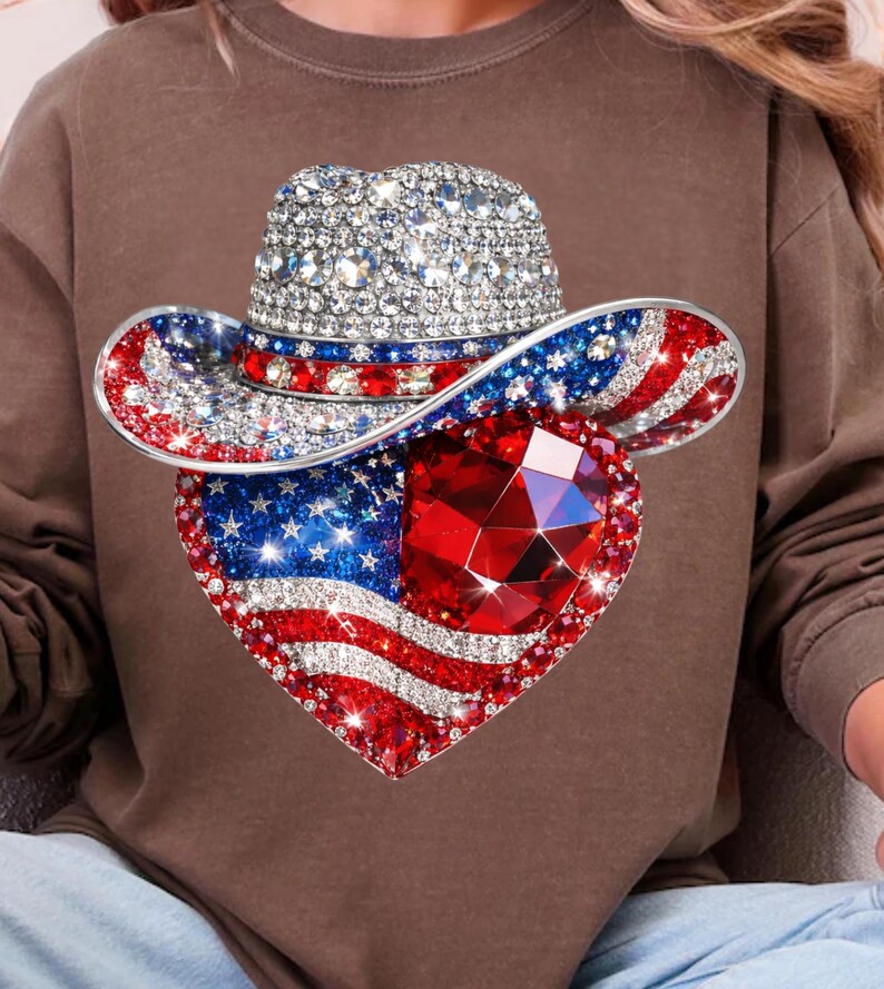 May include: A bedazzled cowboy hat with a heart-shaped design. The hat features a silver crown and a brim adorned with red, white, and blue crystals, forming the American flag. A large, faceted red gem is at the heart's center.