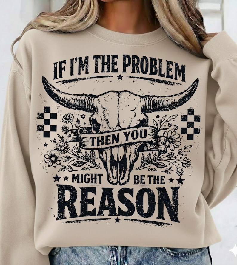 May include: Beige sweatshirt with a graphic of a bull skull, flowers, and the text "IF I'M THE PROBLEM THEN YOU MIGHT BE THE REASON". The design is in black and white, with a vintage, distressed look.