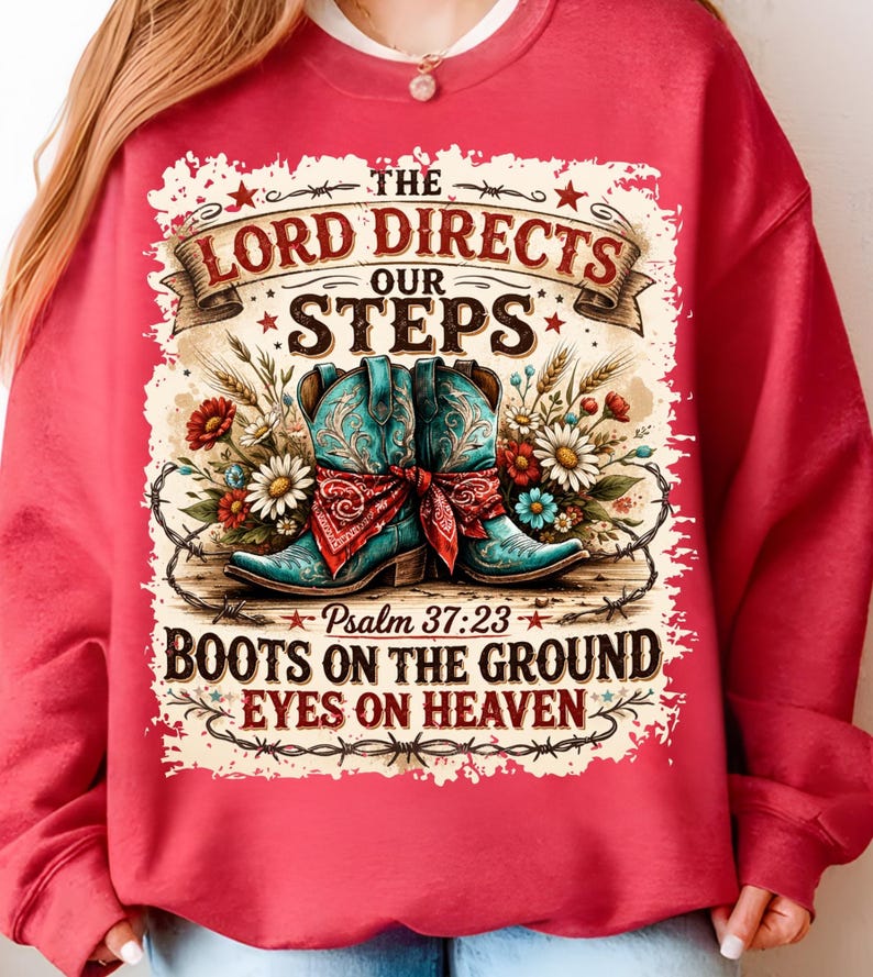 May include: Red sweatshirt with a graphic featuring turquoise cowboy boots, floral accents, and the text "The Lord Directs Our Steps." The design includes the Bible verse Psalm 37:23 and the phrase "Boots on the Ground, Eyes on Heaven."