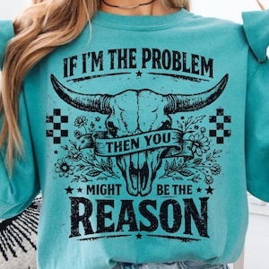 May include: Teal sweatshirt with a graphic of a bull skull, flowers, and the text "IF I'M THE PROBLEM THEN YOU MIGHT BE THE REASON." The design is in black and white, with a vintage, distressed look.