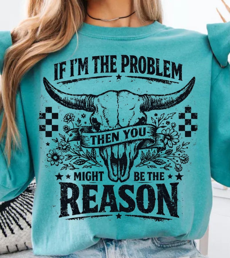 May include: Teal sweatshirt with a graphic of a bull skull, flowers, and the text "IF I'M THE PROBLEM THEN YOU MIGHT BE THE REASON." The design is in black and white, with a vintage, distressed look.