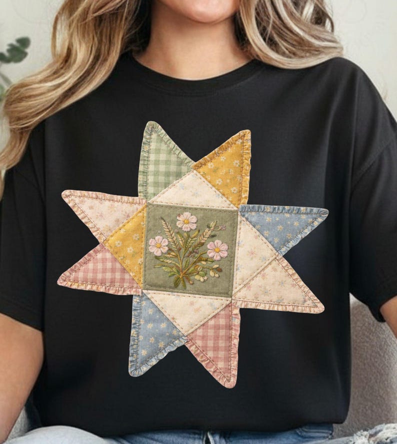 May include: Black t-shirt featuring a colorful starburst design. The starburst is made of patchwork fabric in various pastel colors, with a floral centerpiece. The design has a vintage, handcrafted aesthetic.