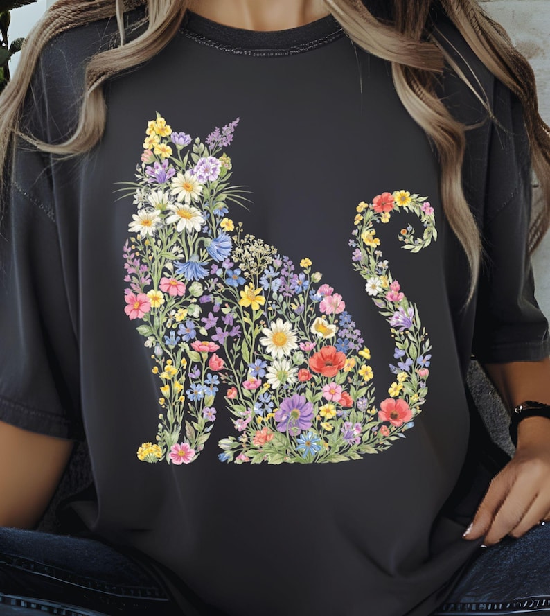 May include: Dark gray t-shirt featuring a floral cat design. The cat silhouette is filled with colorful flowers in shades of yellow, pink, purple, and blue. The shirt has a relaxed fit and short sleeves, perfect for casual wear.