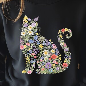May include: Black sweatshirt featuring a floral cat design. The cat silhouette is filled with a variety of colorful flowers, including daisies, poppies, and lavender. The flowers are in shades of pink, yellow, blue, and purple, creating a vibrant and eye-catching design.
