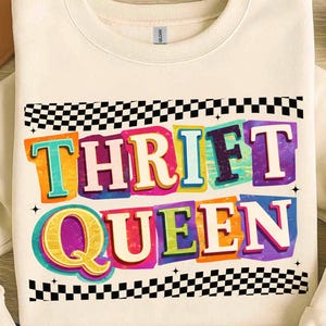 Puede incluir: Sudadera de color crema con el texto "THRIFT QUEEN" en letras coloridas de estilo retro. El diseño incluye un patrón de cuadros blancos y negros en la parte superior e inferior, con una estrella a cada lado del texto.