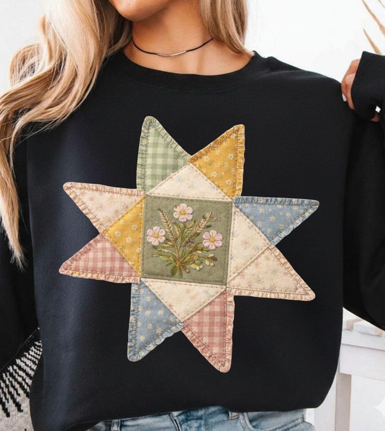 May include: Black sweatshirt featuring a large, colorful star design. The star is made of patchwork fabric in various pastel colors, with a floral embroidered center. The design gives a vintage, handcrafted aesthetic.