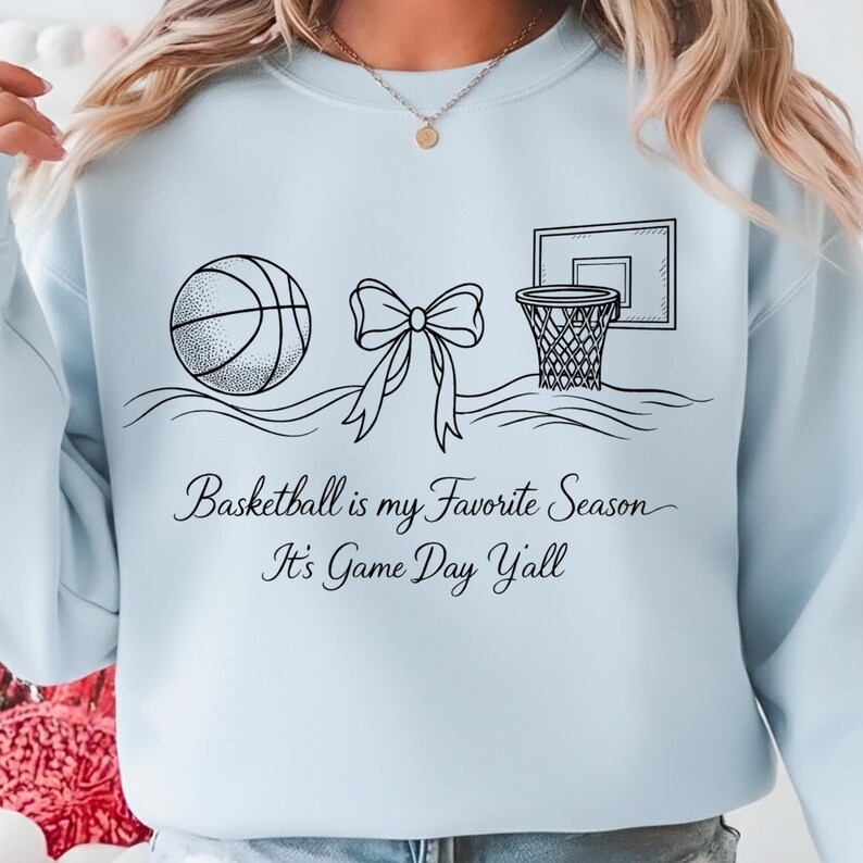 May include: Light blue sweatshirt with a black graphic of a basketball, bow, and basketball hoop. The text "Basketball is my Favorite Season It's Game Day Yall" is printed below the graphic.