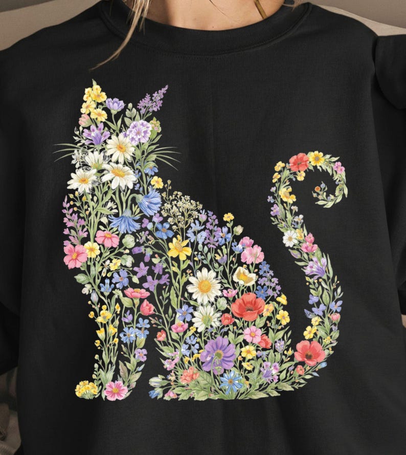 May include: Black sweatshirt featuring a floral cat design. The cat silhouette is composed of colorful flowers, including daisies, poppies, and lavender. The flowers are in shades of pink, yellow, blue, and purple.